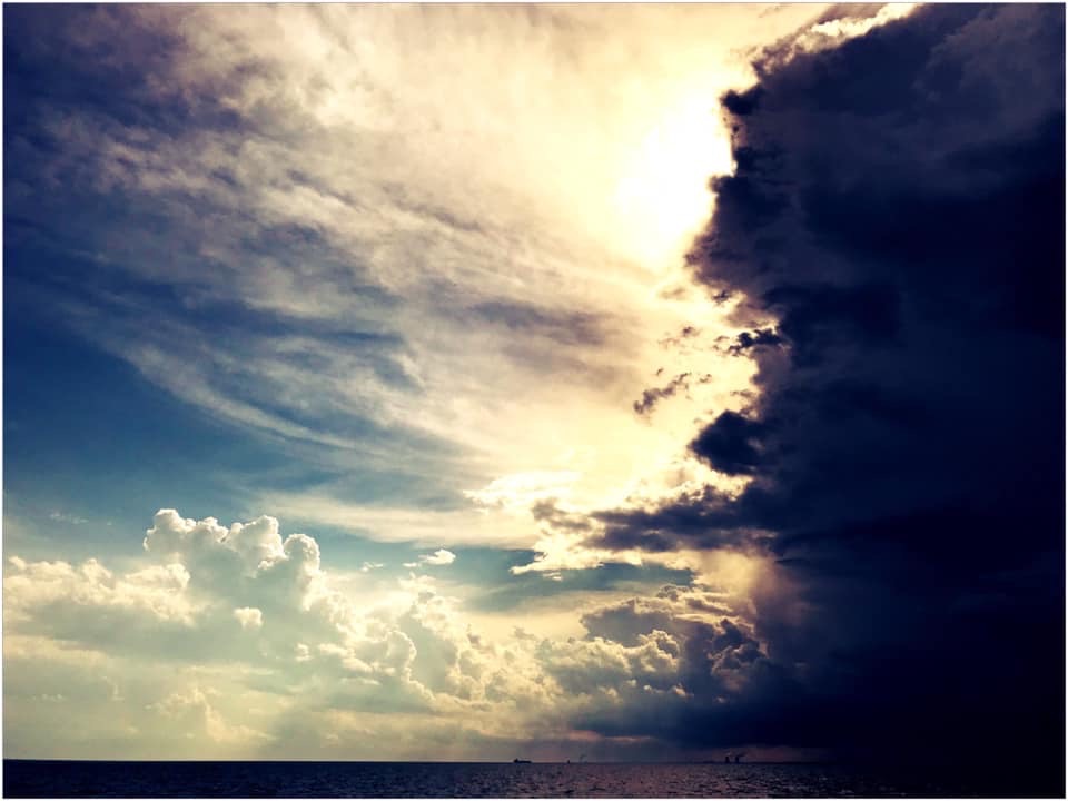 storm coming into the sun filled sky over lake