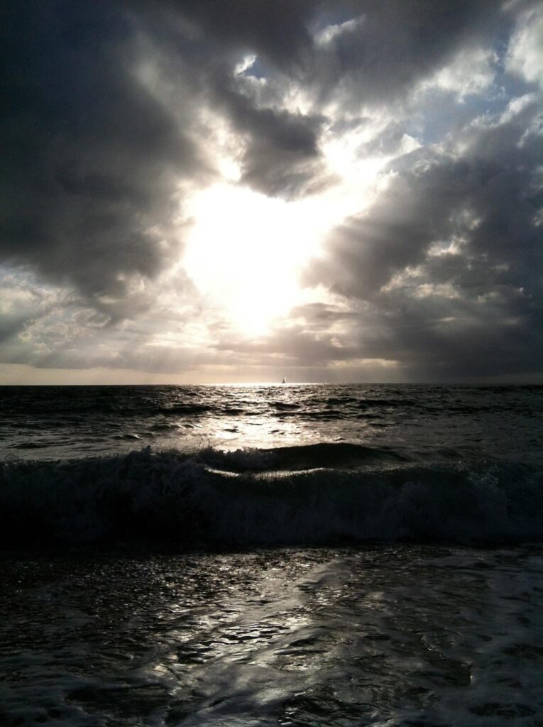 ocean with clouds parting in shape of heart and sunshine coming through